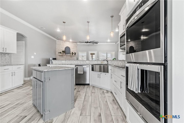 kitchen with white cabinetry, a center island, stainless steel appliances, and hanging light fixtures