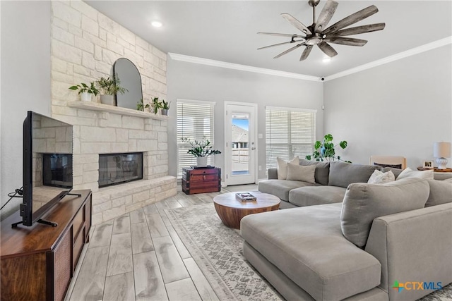 living room with ceiling fan, crown molding, and a stone fireplace