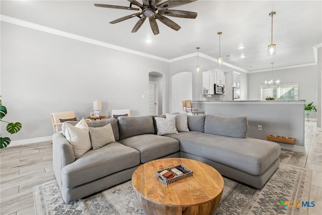 living room with ceiling fan with notable chandelier and ornamental molding