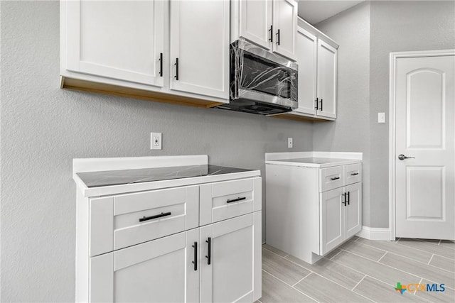 washroom featuring wood finish floors, a textured wall, and baseboards