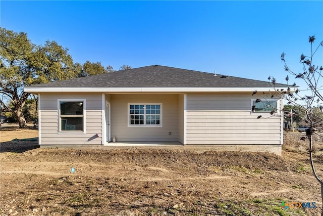 rear view of property featuring roof with shingles and a patio