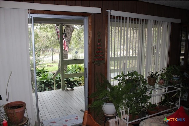 doorway to outside with wood walls