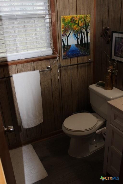 bathroom featuring vanity, toilet, and wood walls