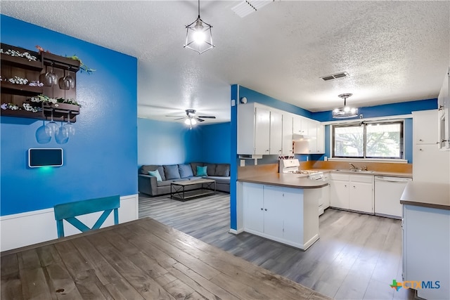 kitchen featuring light wood-type flooring, a textured ceiling, pendant lighting, white cabinets, and white appliances