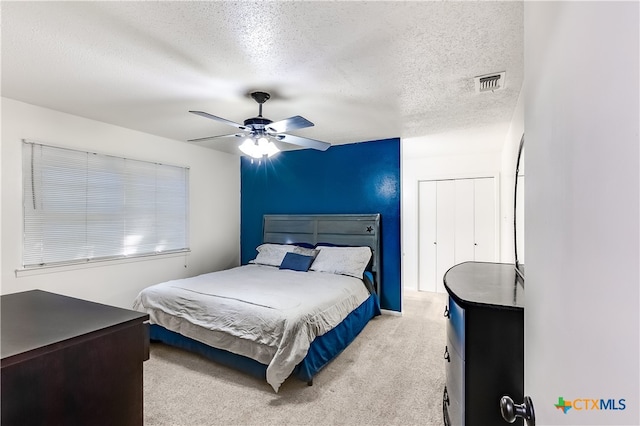 bedroom with light carpet, a textured ceiling, ceiling fan, and a closet