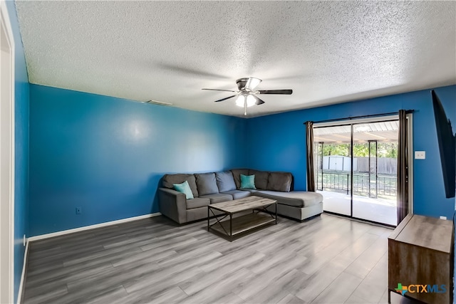 living room with ceiling fan, a textured ceiling, and light hardwood / wood-style floors