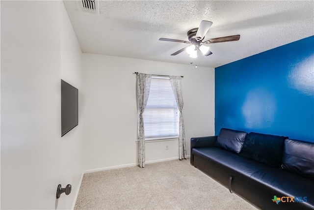 sitting room with light colored carpet, a textured ceiling, and ceiling fan