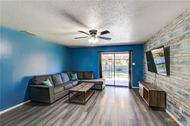 living room featuring hardwood / wood-style floors, ceiling fan, and a textured ceiling