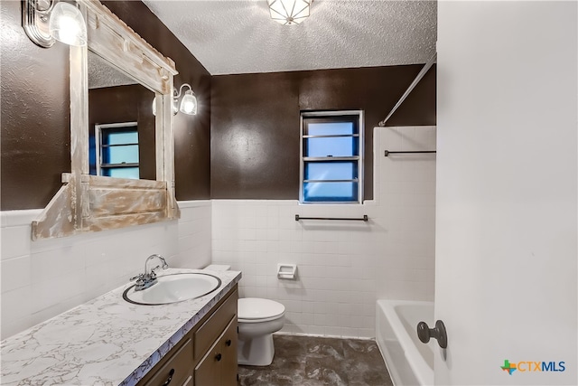 bathroom with toilet, vanity, a textured ceiling, and tile walls