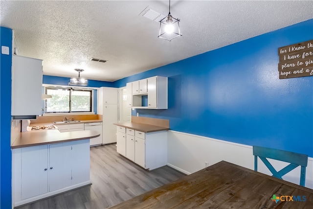 kitchen featuring white cabinetry, white dishwasher, decorative light fixtures, and light hardwood / wood-style flooring