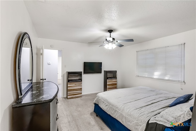 bedroom with a textured ceiling, light carpet, and ceiling fan