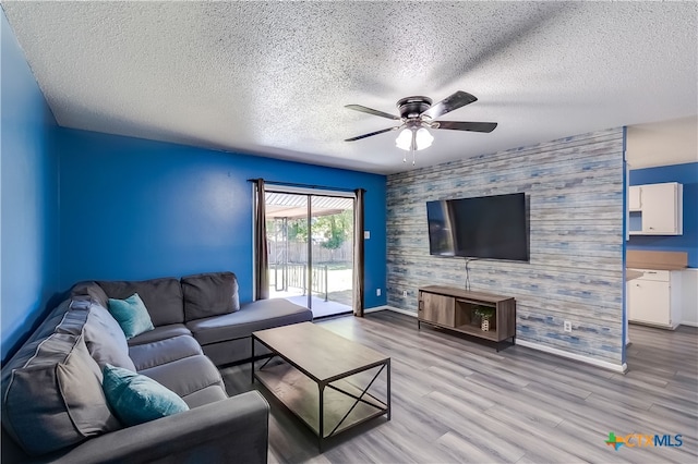 living room featuring light hardwood / wood-style floors, a textured ceiling, and ceiling fan