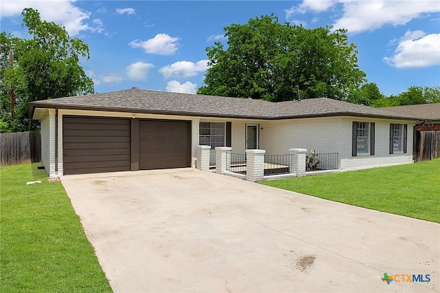 ranch-style home with an attached garage, driveway, fence, and a front lawn