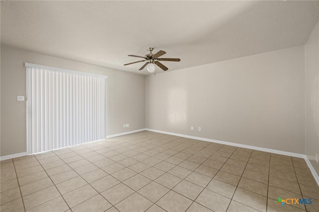 empty room with light tile patterned floors, baseboards, ceiling fan, and a textured ceiling