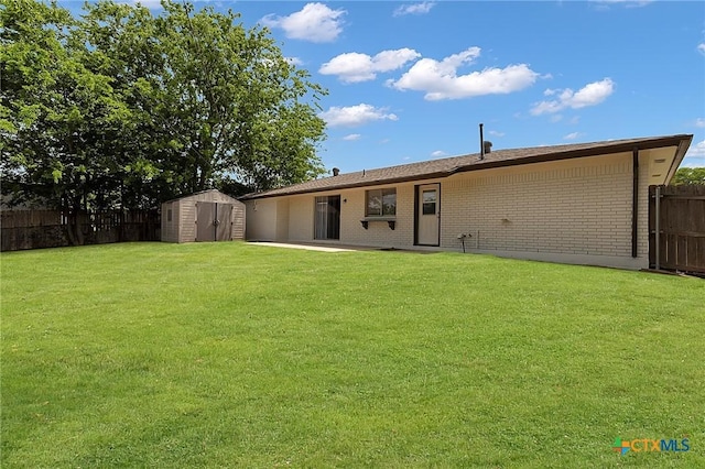 back of house featuring a yard, an outbuilding, brick siding, fence, and a storage unit