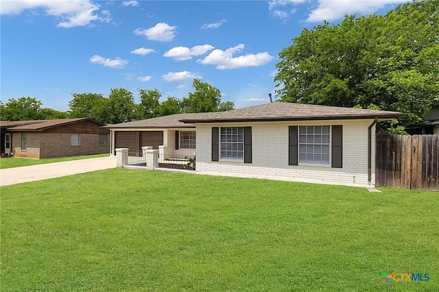 view of front facade featuring fence, concrete driveway, brick siding, and a front yard
