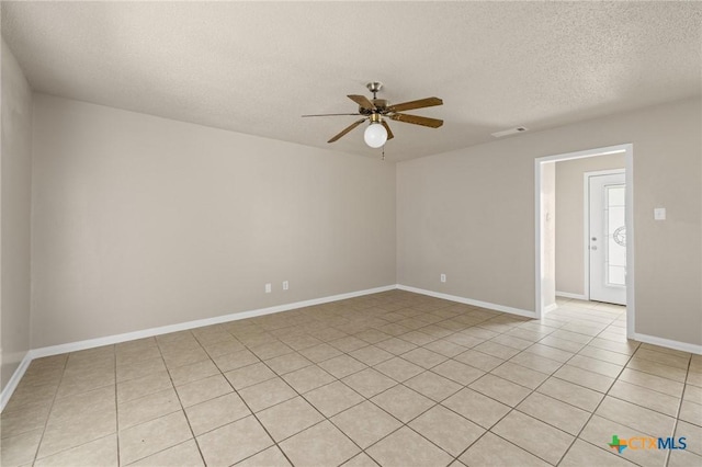 unfurnished room with a textured ceiling, light tile patterned flooring, visible vents, a ceiling fan, and baseboards