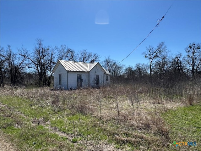 view of property exterior with metal roof and an outdoor structure