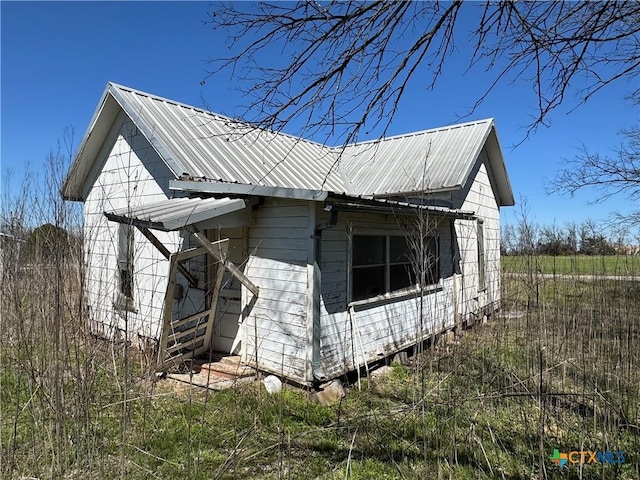 view of property exterior featuring metal roof and an outdoor structure