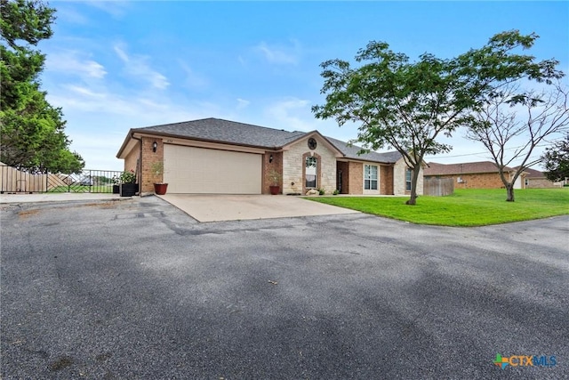 ranch-style house with fence, brick siding, driveway, a garage, and a front lawn
