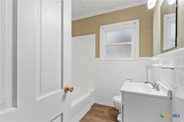 bathroom with a bathtub, vanity, hardwood / wood-style flooring, tile walls, and toilet