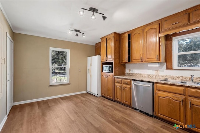 kitchen with sink, stainless steel appliances, light stone counters, crown molding, and light wood-type flooring