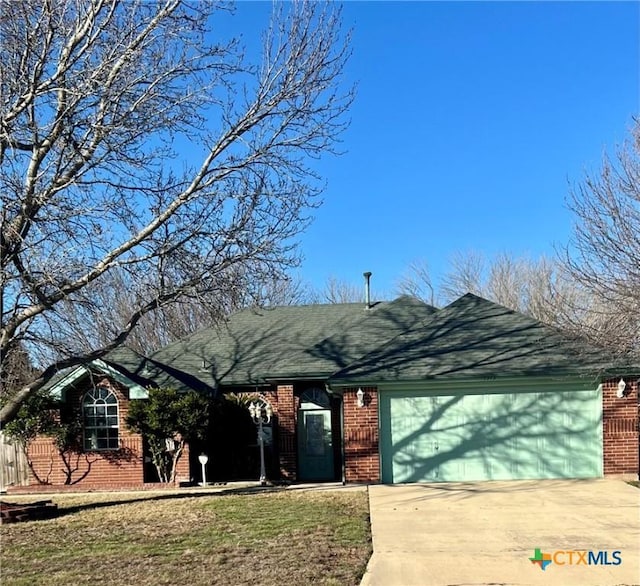 ranch-style house with an attached garage, driveway, a shingled roof, and brick siding