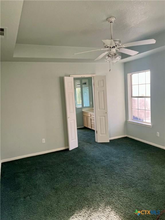 empty room with dark colored carpet, visible vents, and baseboards