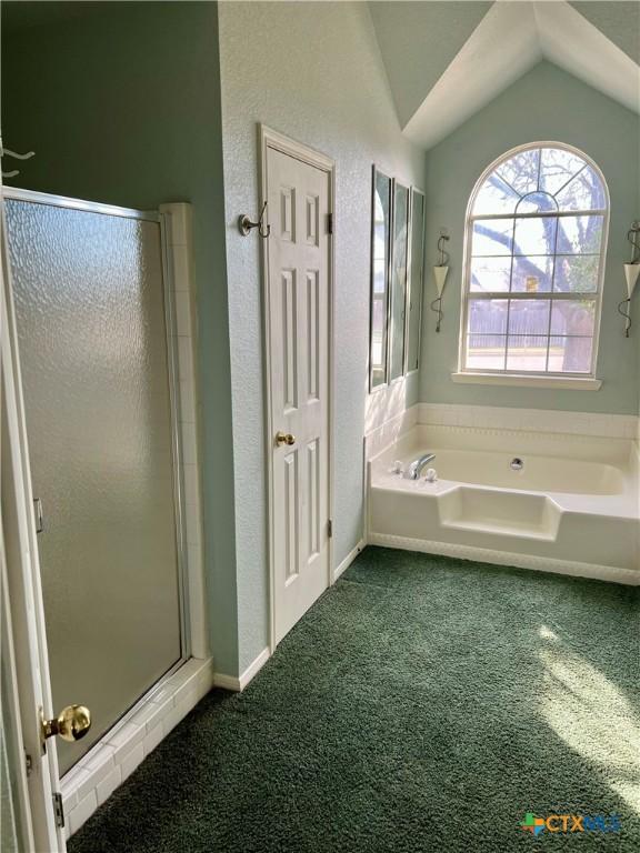 full bathroom featuring lofted ceiling, carpet floors, a stall shower, and a bath