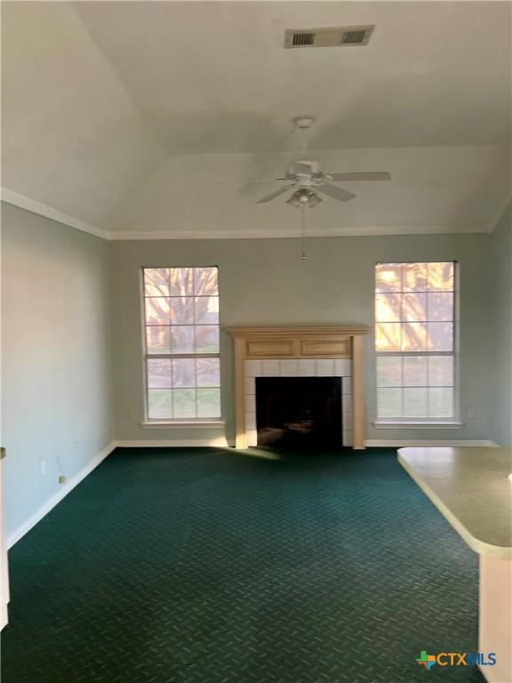 unfurnished living room with carpet, visible vents, vaulted ceiling, and a tiled fireplace