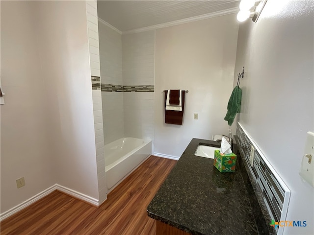 bathroom featuring wood-type flooring, tiled shower / bath, sink, and crown molding