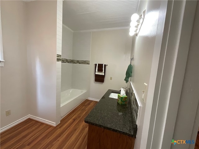 bathroom featuring ornamental molding, wood-type flooring, a tub, and vanity