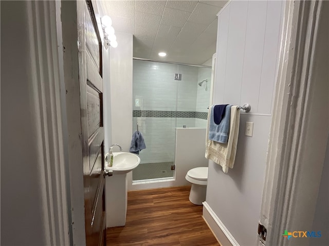 bathroom with toilet, sink, hardwood / wood-style floors, and a shower with shower door