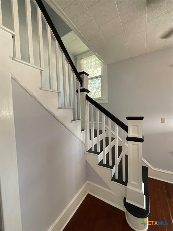 1203 E Third St, Hallettsville, TX 77954 - staircase with baseboards and wood finished floors