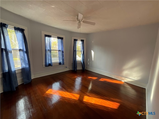 spare room with plenty of natural light, dark wood-type flooring, and ceiling fan