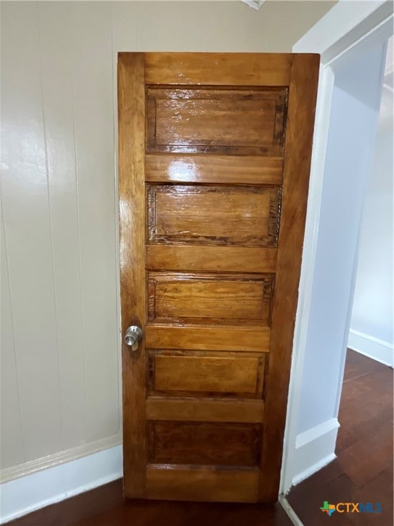 interior details featuring hardwood / wood-style flooring and wooden walls