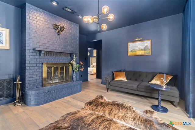 2406 Northwoods Dr, New Braunfels, TX 78132 - living area featuring wood finished floors, a brick fireplace, and a chandelier