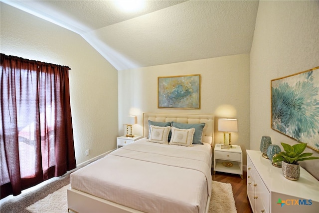 bedroom featuring a textured ceiling, multiple windows, hardwood / wood-style floors, and vaulted ceiling