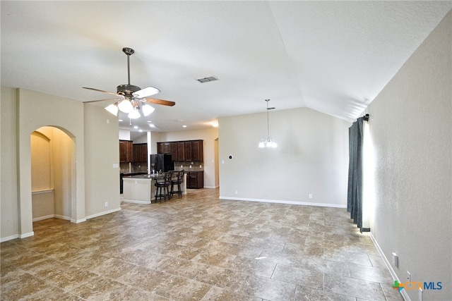 unfurnished living room with ceiling fan with notable chandelier and vaulted ceiling