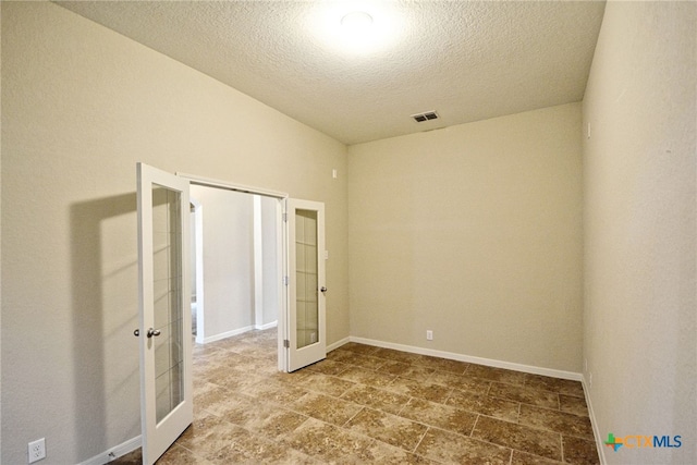 spare room featuring french doors and a textured ceiling