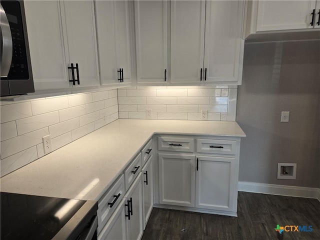 kitchen with dark wood-style floors, stainless steel microwave, white cabinets, and light countertops