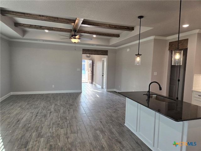 kitchen with dark wood-style flooring, beam ceiling, open floor plan, white cabinets, and a sink