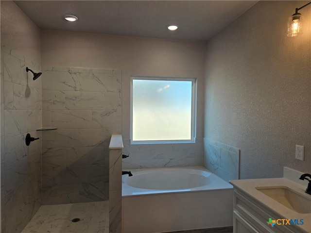 bathroom with a textured wall, a tile shower, vanity, a bath, and recessed lighting