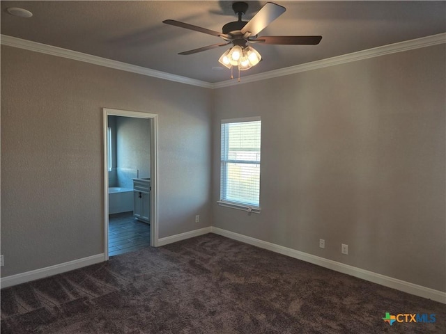 unfurnished bedroom featuring ensuite bathroom, a ceiling fan, baseboards, dark carpet, and crown molding