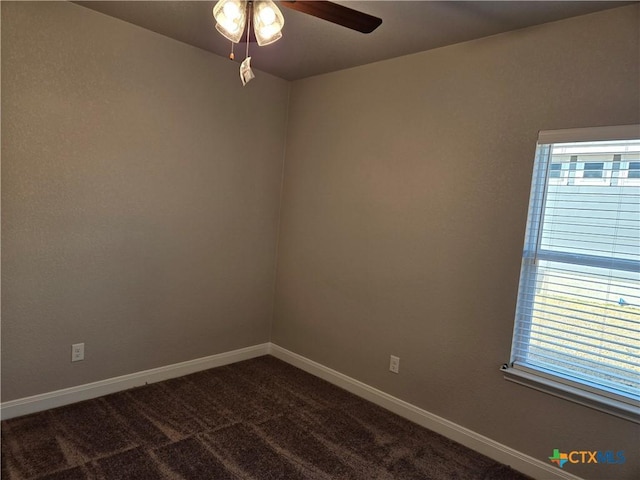 empty room with a healthy amount of sunlight, dark carpet, baseboards, and ceiling fan