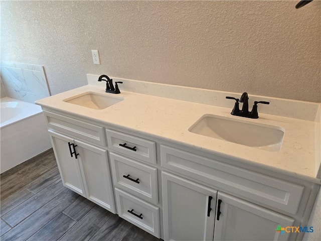 bathroom featuring a textured wall, wood finished floors, and a sink