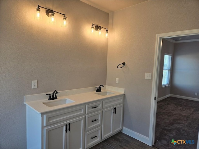 bathroom featuring double vanity, baseboards, a sink, and wood finished floors