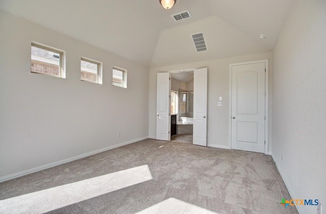 unfurnished bedroom featuring lofted ceiling, ensuite bath, and light carpet