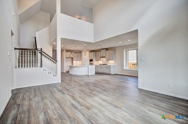 unfurnished living room with a high ceiling and hardwood / wood-style flooring