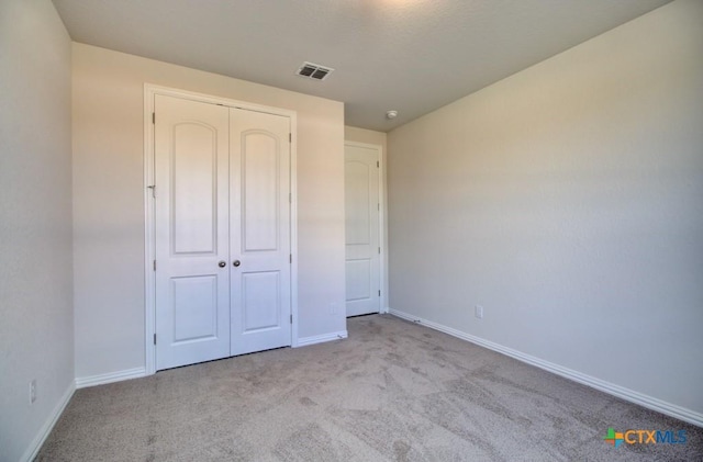 unfurnished bedroom with light carpet and a closet